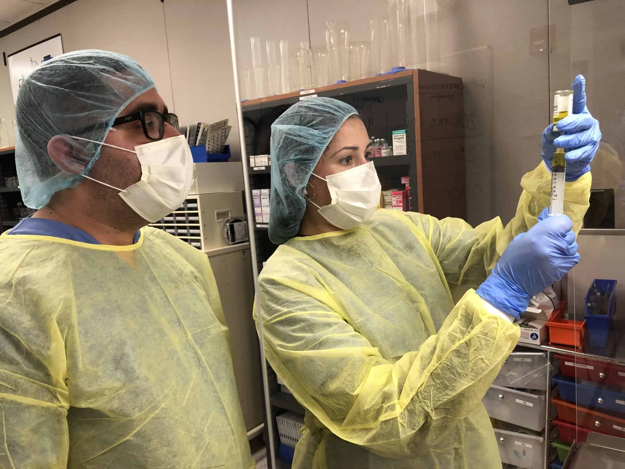 miami pharmacy technician program students in full PPE dispensing liquid from a bottle