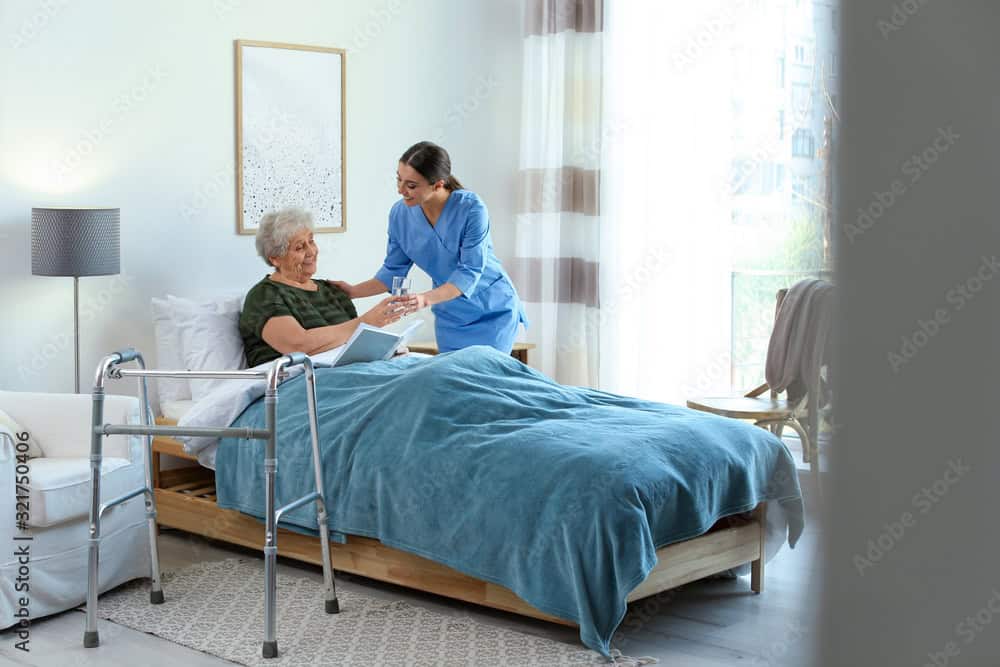 ASN nursing program student working as an RN as a hospice nurse - nurse helping elderly patient in her bed