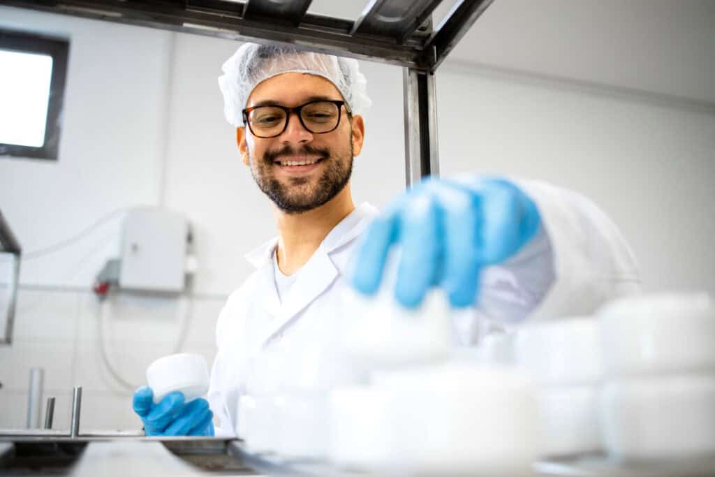 A male pharmacy technician working in a laboratory or factory setting