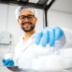 A male pharmacy technician working in a laboratory or factory setting