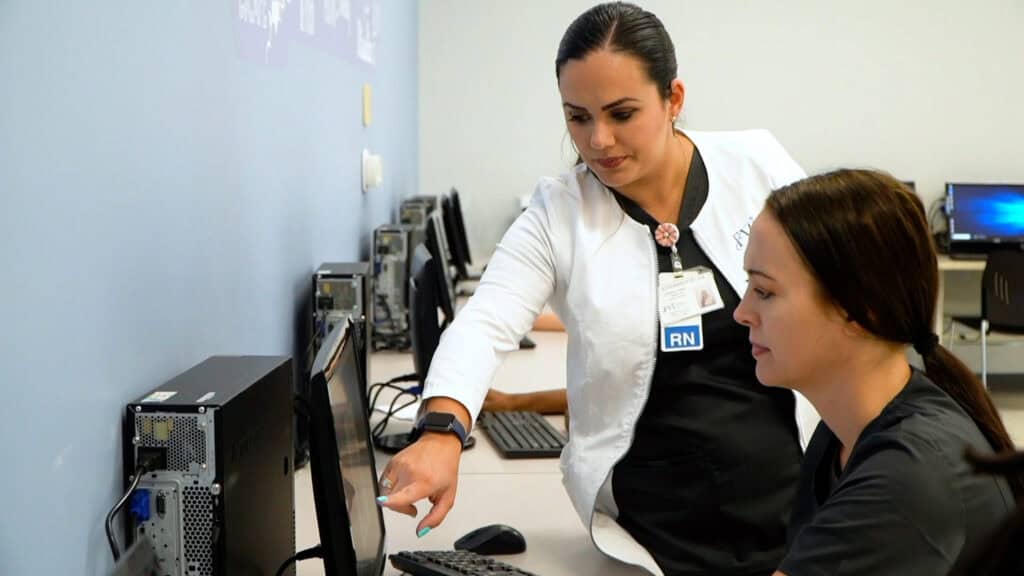 a nursing professor showing the laptop to a Miami ASN nursing school student