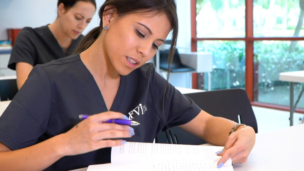 Miramar ASN nursing school student is studying from a book in a classroom with another student doing the same in the background