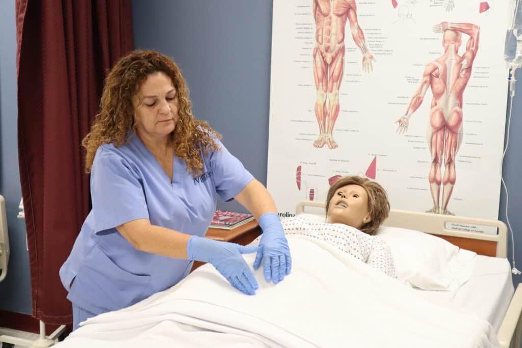 A Miami Patient Care Technician school student performs chest compressions on a simulation