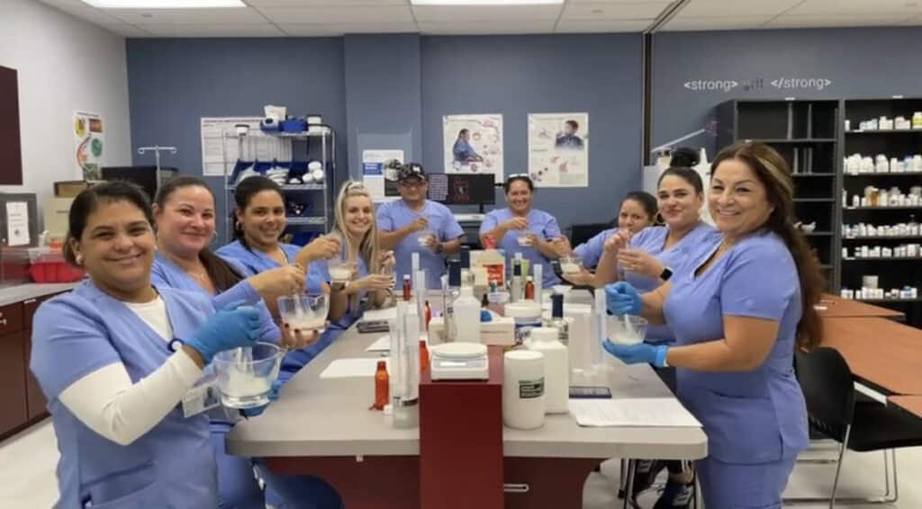 miami pharmacy technician school students smiling at the camera while they practice
