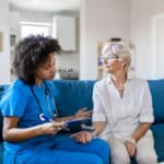 florida RN Nurse Checking Senior Patient's Blood Pressure in the Livingroom. Female Doctor Measuring Blood Pressure of Senior Woman.