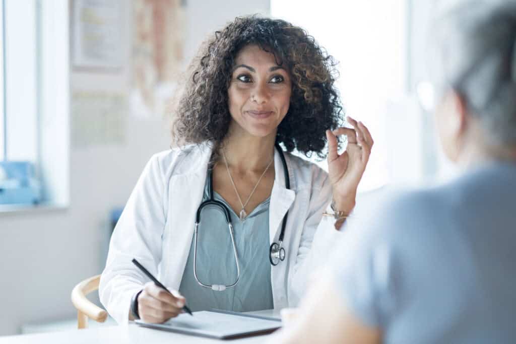 florida health coach sitting at a table with a pen in hand ready to write sitting across from a client