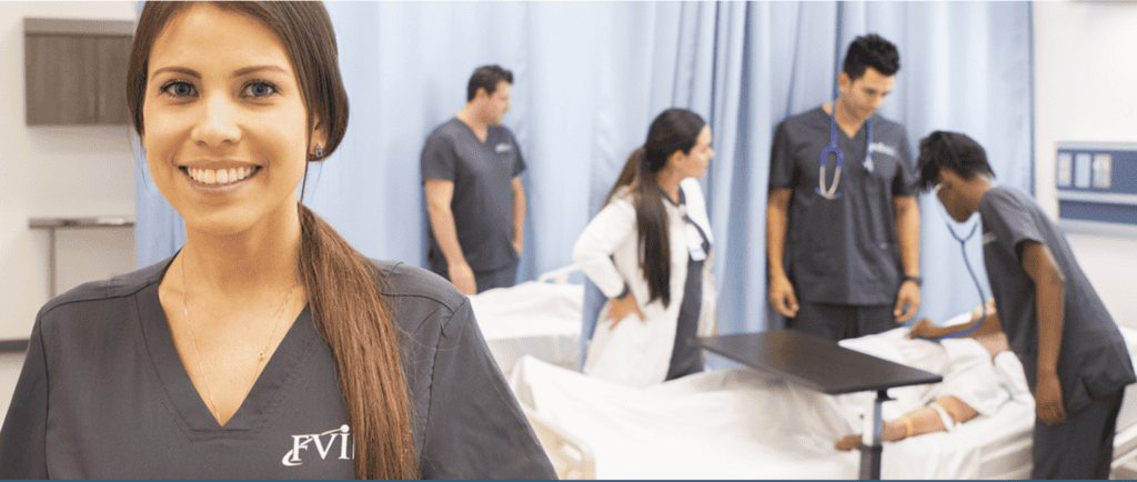 nursing students posing in front of other nursing students pracitcing