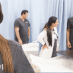 nursing students posing in front of other nursing students pracitcing