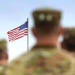 Service member facing the American flag in the background.
