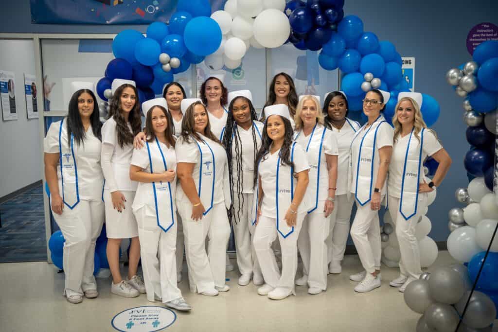 FVI Miramar ASN degree - nursing school graduates posing in front of a balloon arch in the FVI Miramar lobby after a Pinning Ceremony