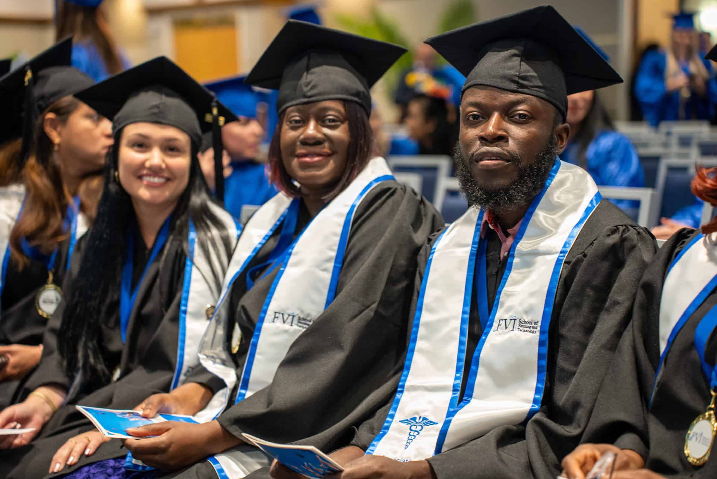 A group of florida ASN nursing program graduates sitting at an FVI graduation ceremony in their robes with their FVI stoles