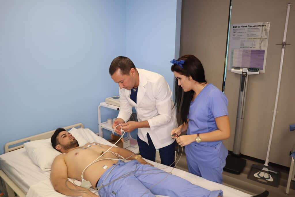 Two medical assistant Students practice hands-on under the supervision of an instructor in a skills lab