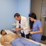 Two medical assistant Students practice hands-on under the supervision of an instructor in a skills lab