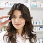 a pharmacist looking at one pill