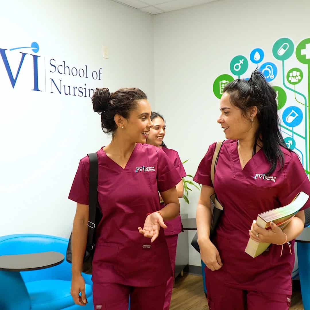 Three Practical Nursing students in Miami smiling and talking at FVI School of Nursing, wearing burgundy uniforms.