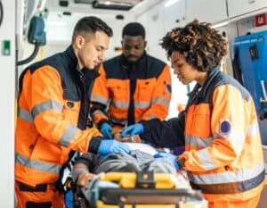 Smiling EMT professional standing in front of an ambulance with a stethoscope.